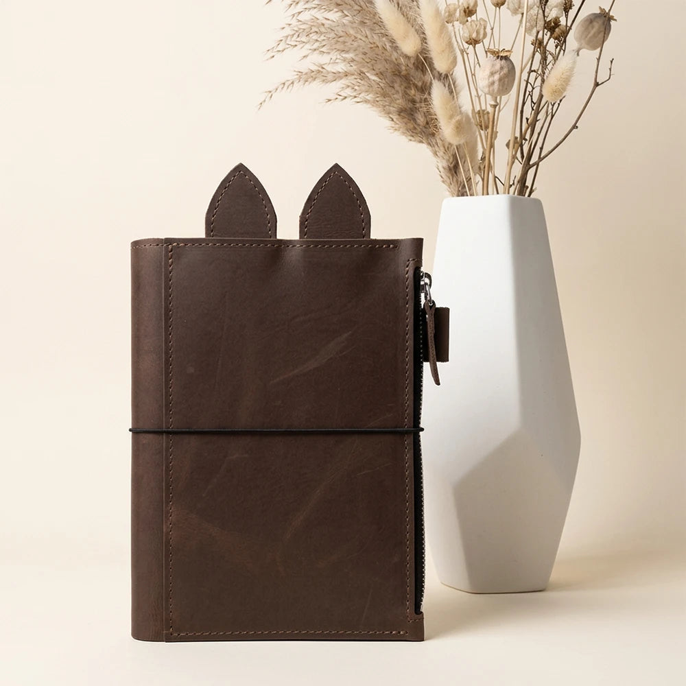 Handmade genuine leather planner cover with zipper pocket, pen holder, decorative ears, and elastic bands.