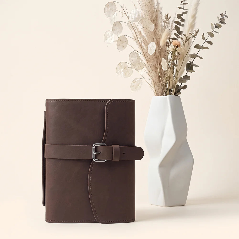 Handmade leather notebook sleeve with organized storage, pen loop, ribbon bookmark, and convenient carrying strap.