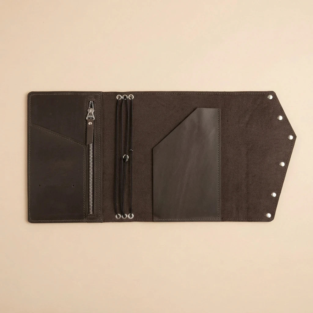 Black leather journal with zipper and card slots on a beige background