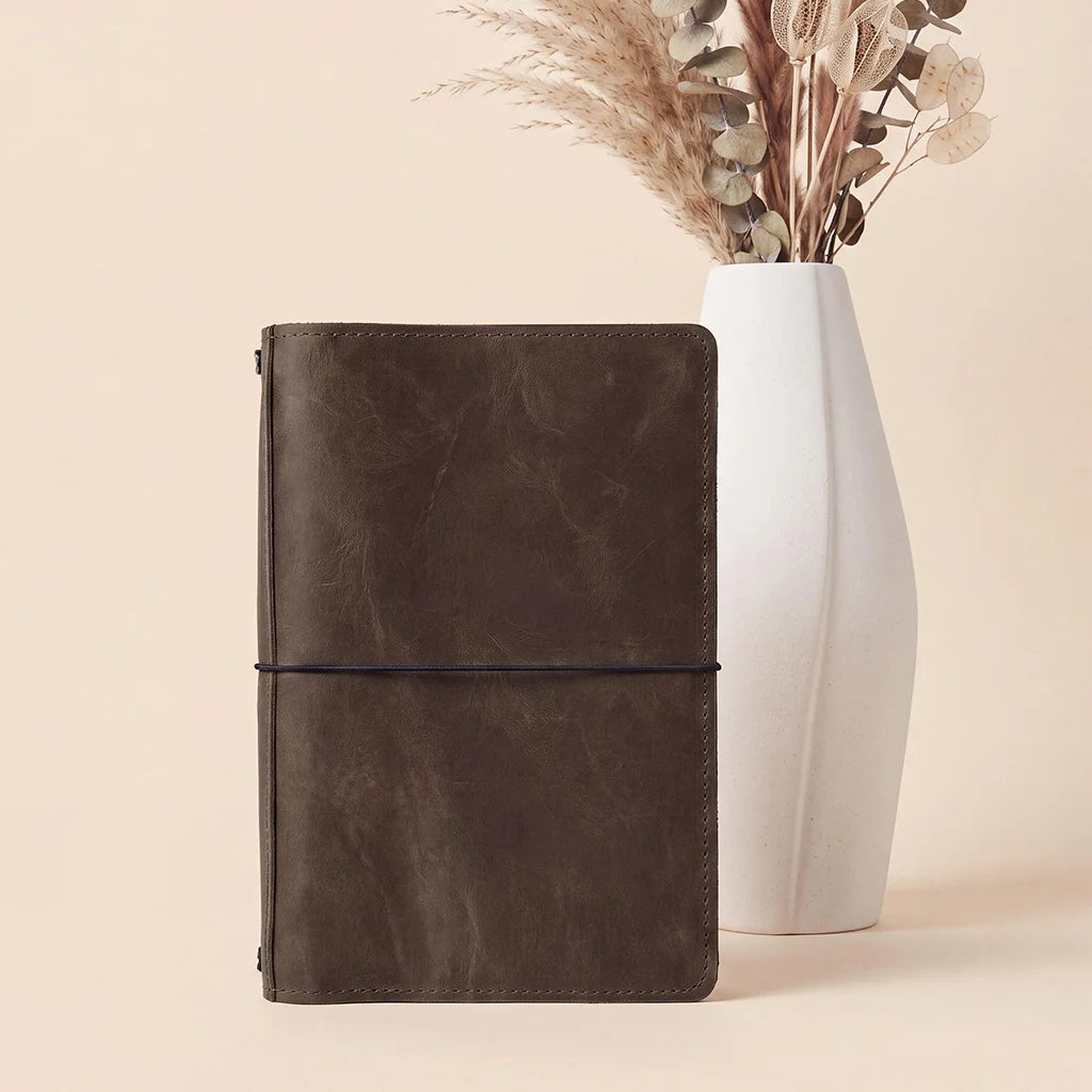 Premium leather notebook cover with secure elastic retention and functional interior organization.