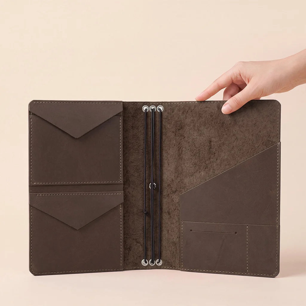 Genuine leather travel notebook cover with interior sleeves and elastic insert retention system.