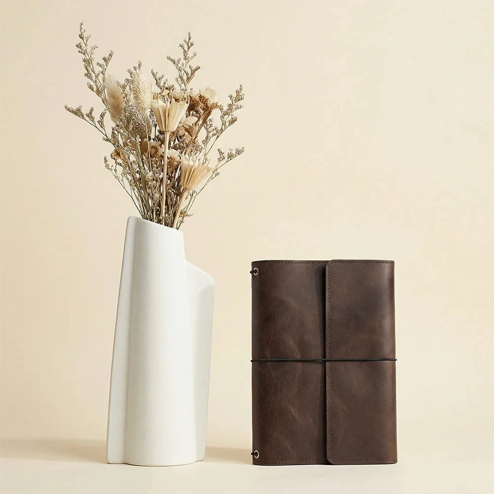 Premium brown leather notebook cover designed with three elastics and organizational pockets inside.
