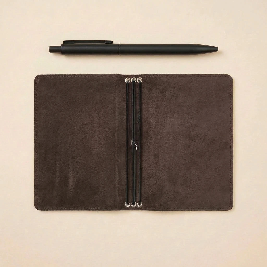 Brown leather notebook with pen on a beige background