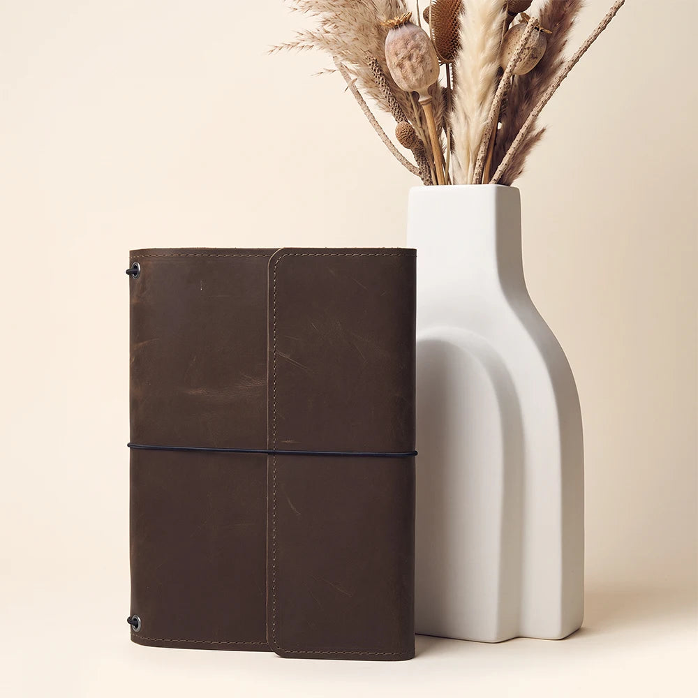 Elegant refillable leather journal cover with pen holder, pockets, and elastic notebook bands.