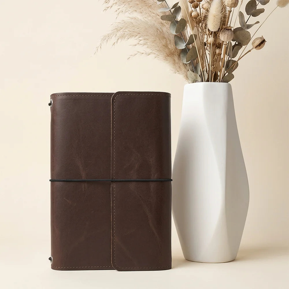 Handmade leather planner sleeve featuring useful storage pockets and a secure elastic pen loop.