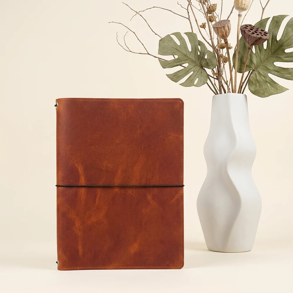 Leather notebook wrap with practical inner organization for multiple refillable journal inserts.