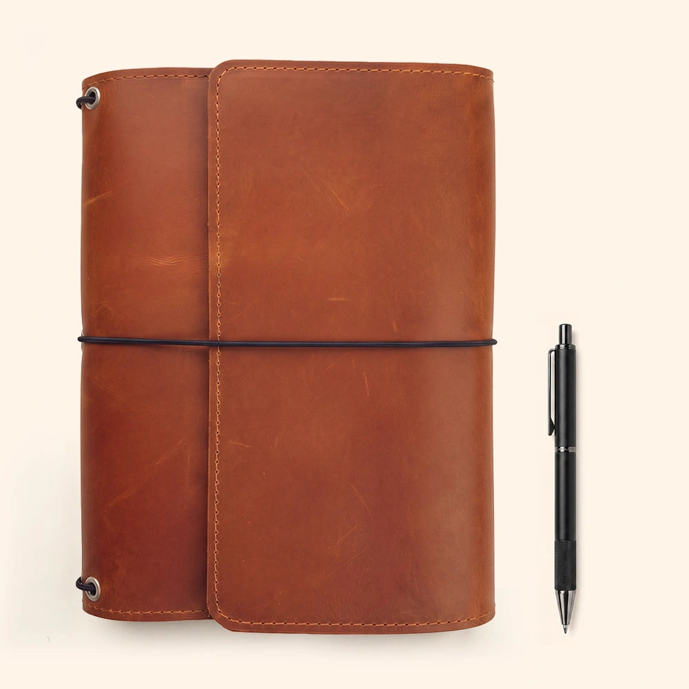 Handmade leather notebook folio including accessory compartments and integrated leather pen keeper.