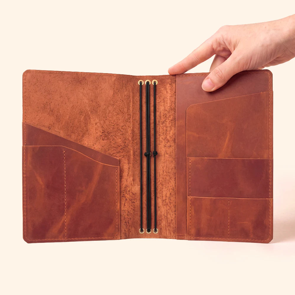 Refillable leather notebook cover with three elastic straps for organizing multiple journal inserts.