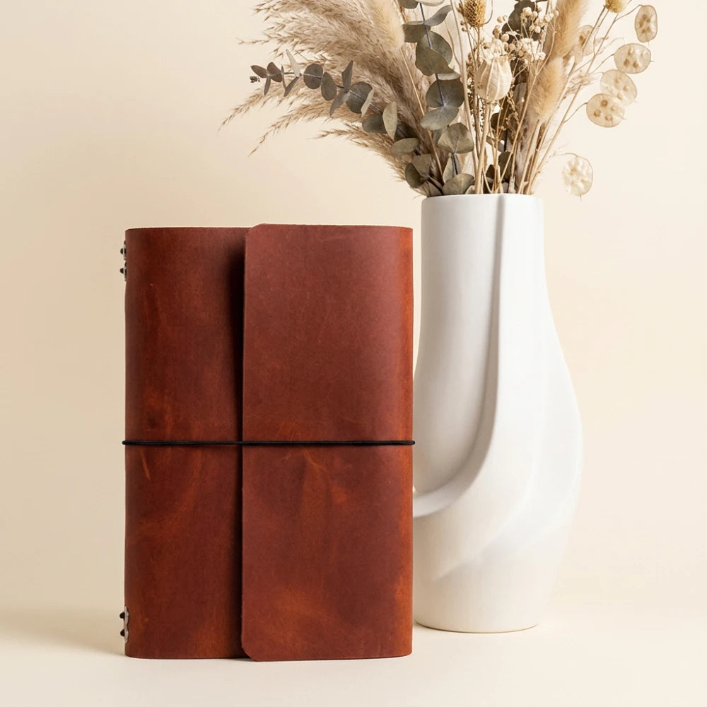 Natural leather journal binder supporting six removable inserts through flexible elastic cords.