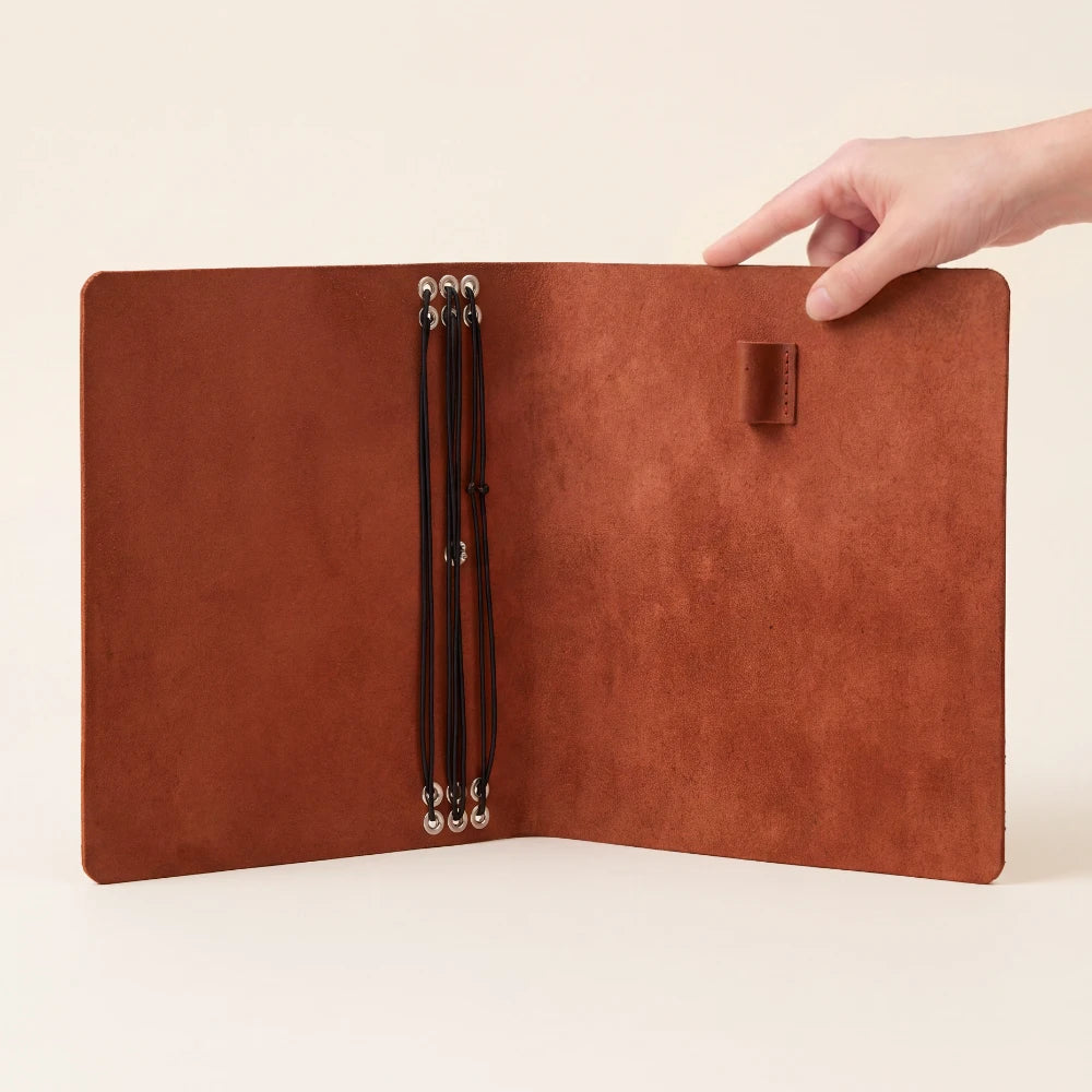 Multipurpose leather notebook wrap accommodating six refills and a conveniently placed pen.