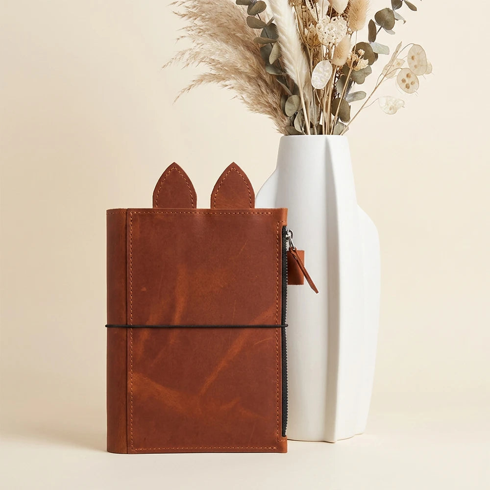 Handmade leather journal organizer shown flat with zipper pocket and pen loop.
