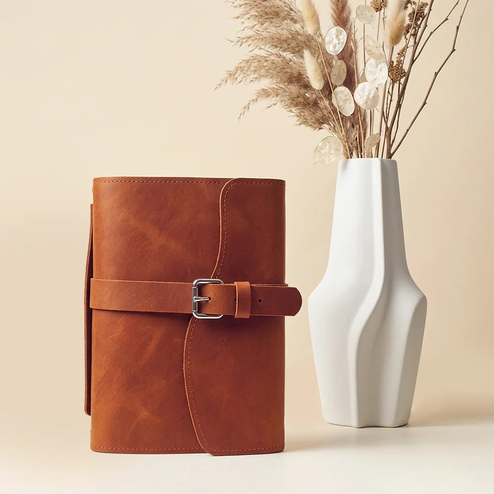 Handcrafted planner cover made from leather with pockets, pen loop, bookmark, and convenient carrying grip.