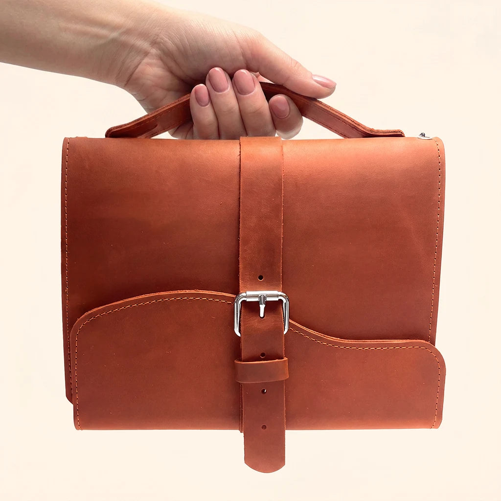 Minimalist leather notebook holder featuring three elastic bands and a practical outer handle.
