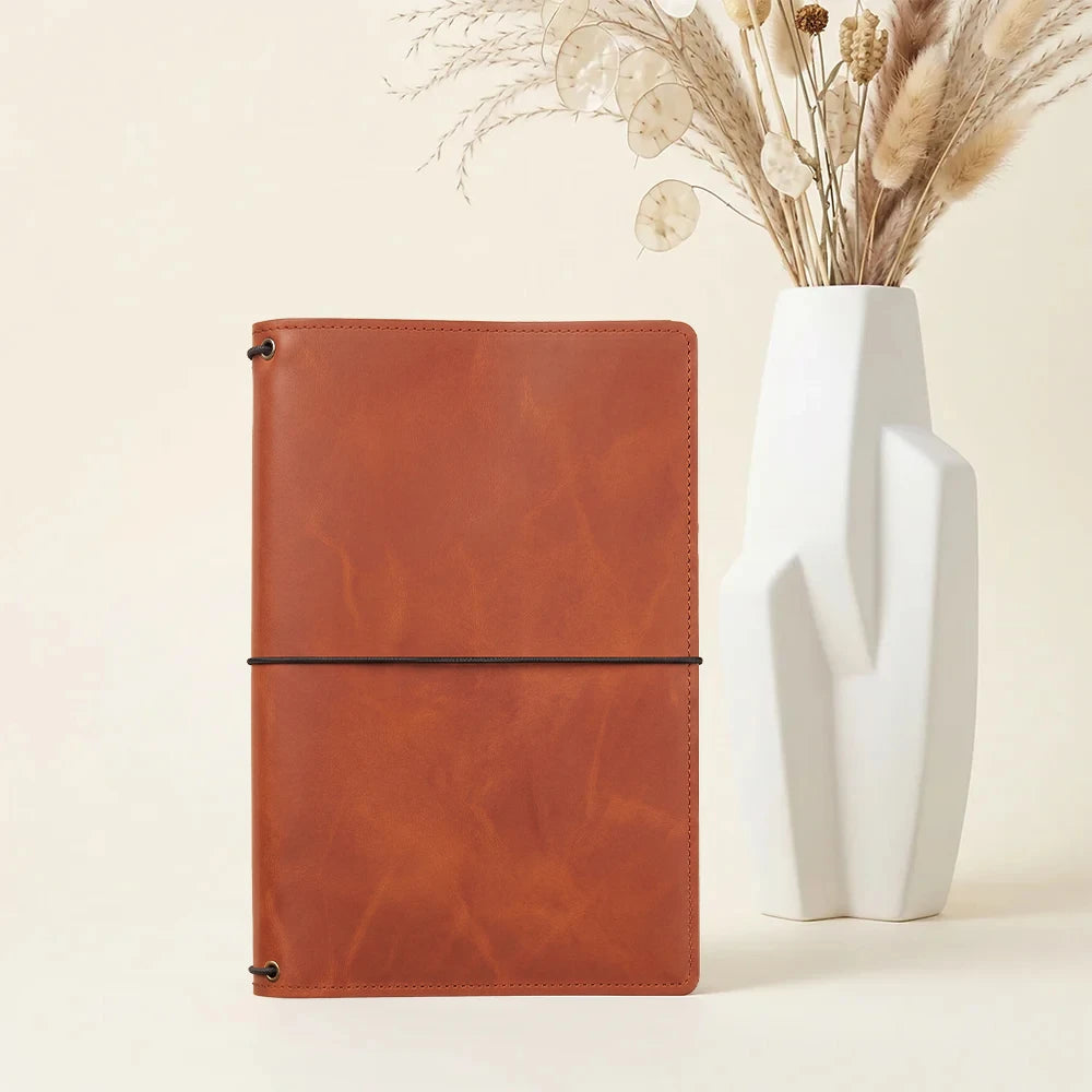 Genuine leather journal holder featuring three refillable elastic bands and storage pockets inside.