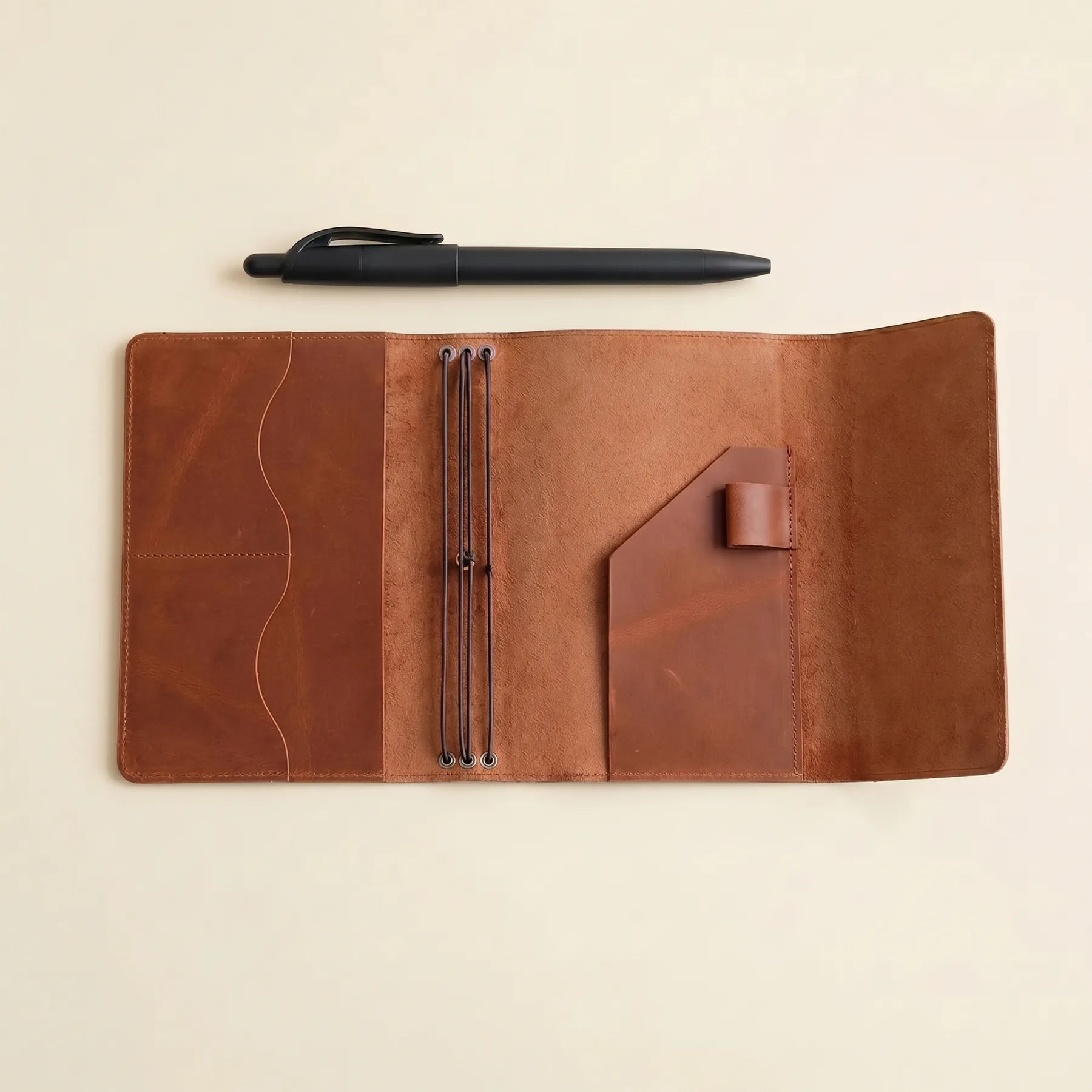Handmade leather notebook cover with pen holder, pockets, and elastic bands.