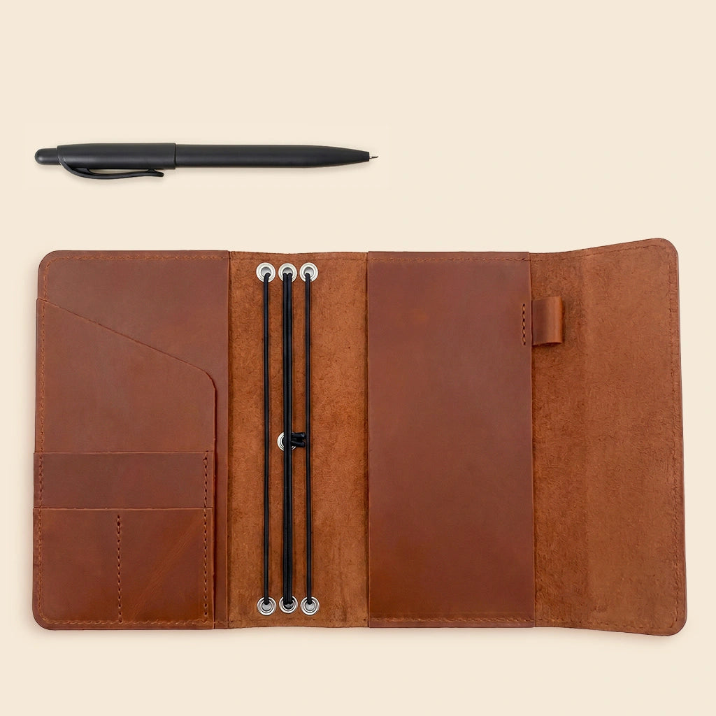 Handmade genuine leather cover protecting refillable notebooks with built-in organizer pockets and pen loop.