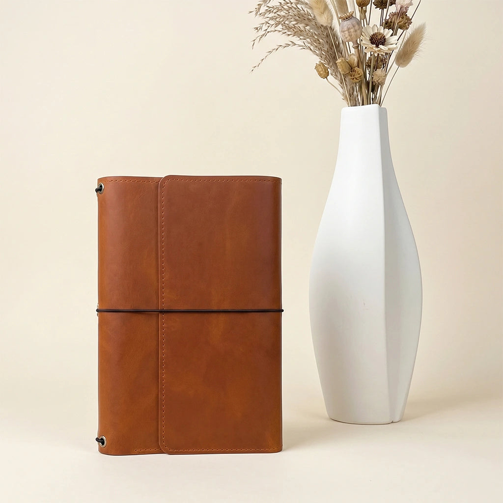 Handmade leather journal holder with flexible elastic cords and built-in pen sleeve.