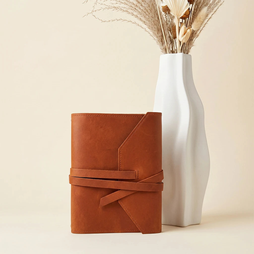 Minimalist leather notebook sleeve with elastic closure and pen holder attachment.