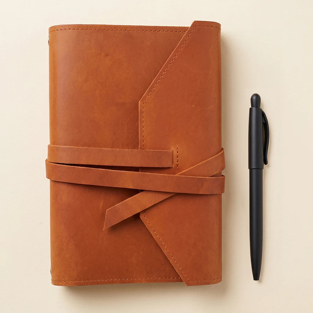 Elegant journal sleeve in leather with pen loop and elastic band closure.