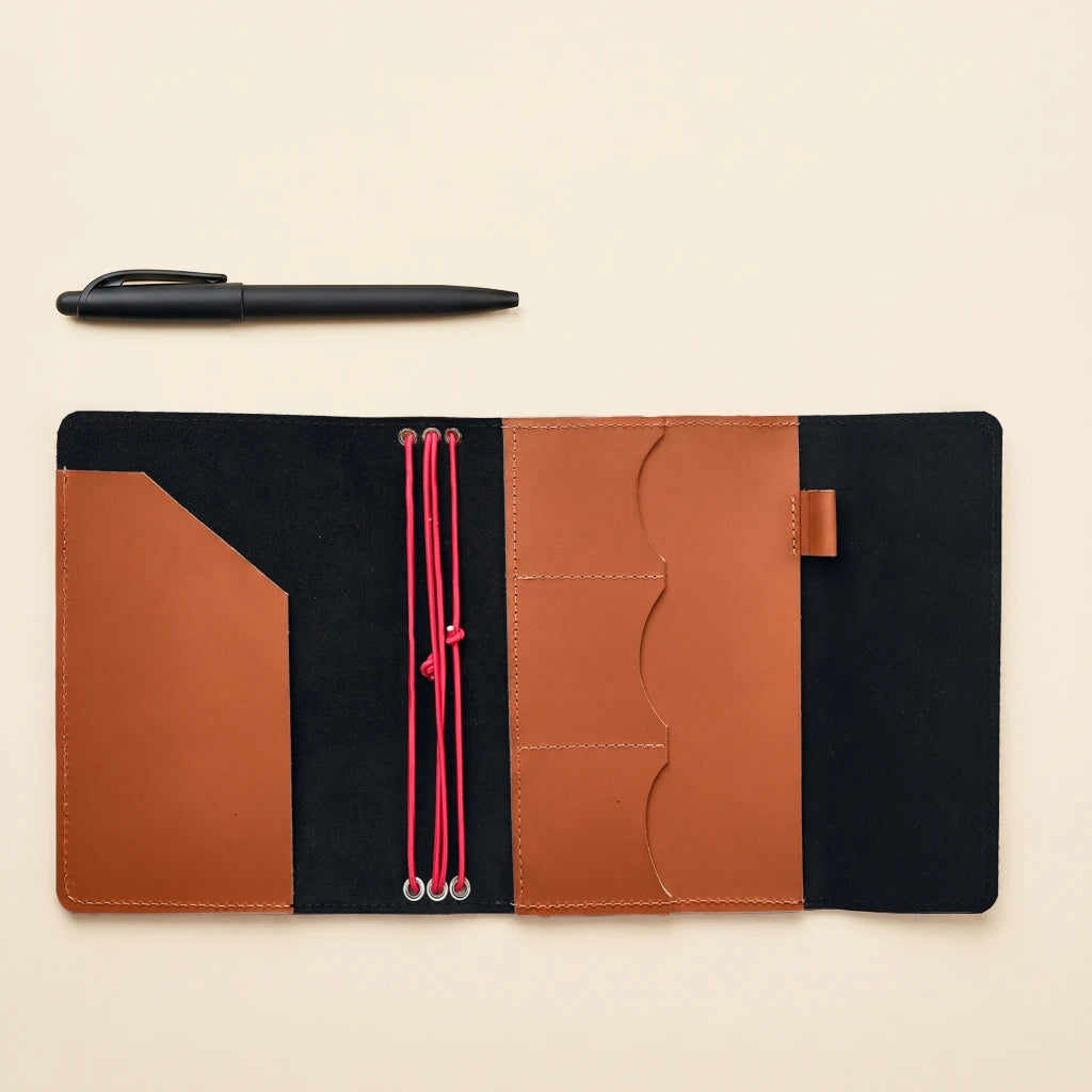 Leather notebook cover featuring elastic bands, storage pockets, and built-in pen loop