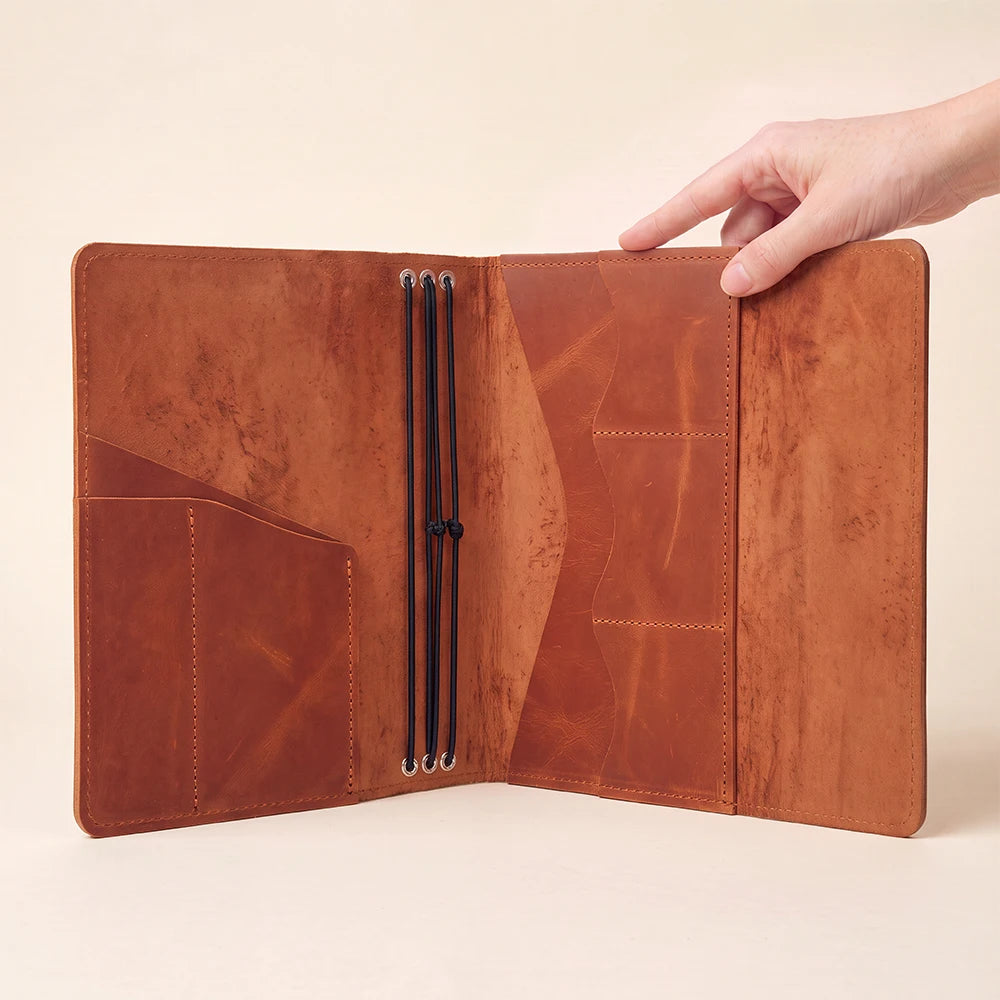 Premium leather journal holder with organized compartments for notebooks, cards, and writing tools.