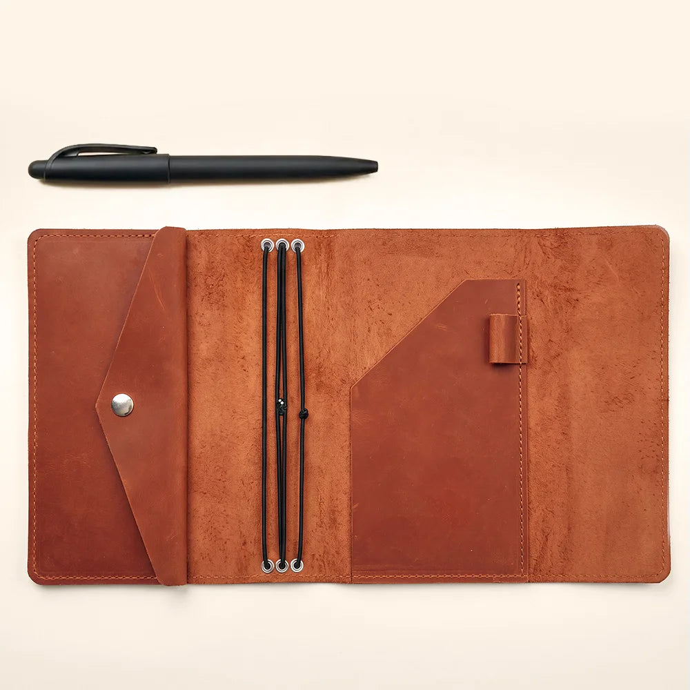 Leather notebook cover designed for travelers with three elastic bands and hidden interior pockets.