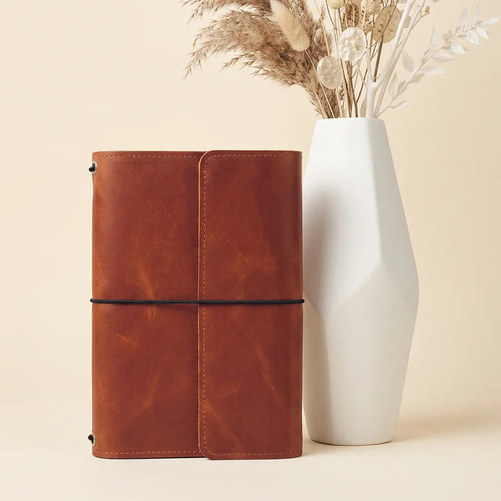 Personalized leather journal case displaying several interior slots and an attached writing tool holder.