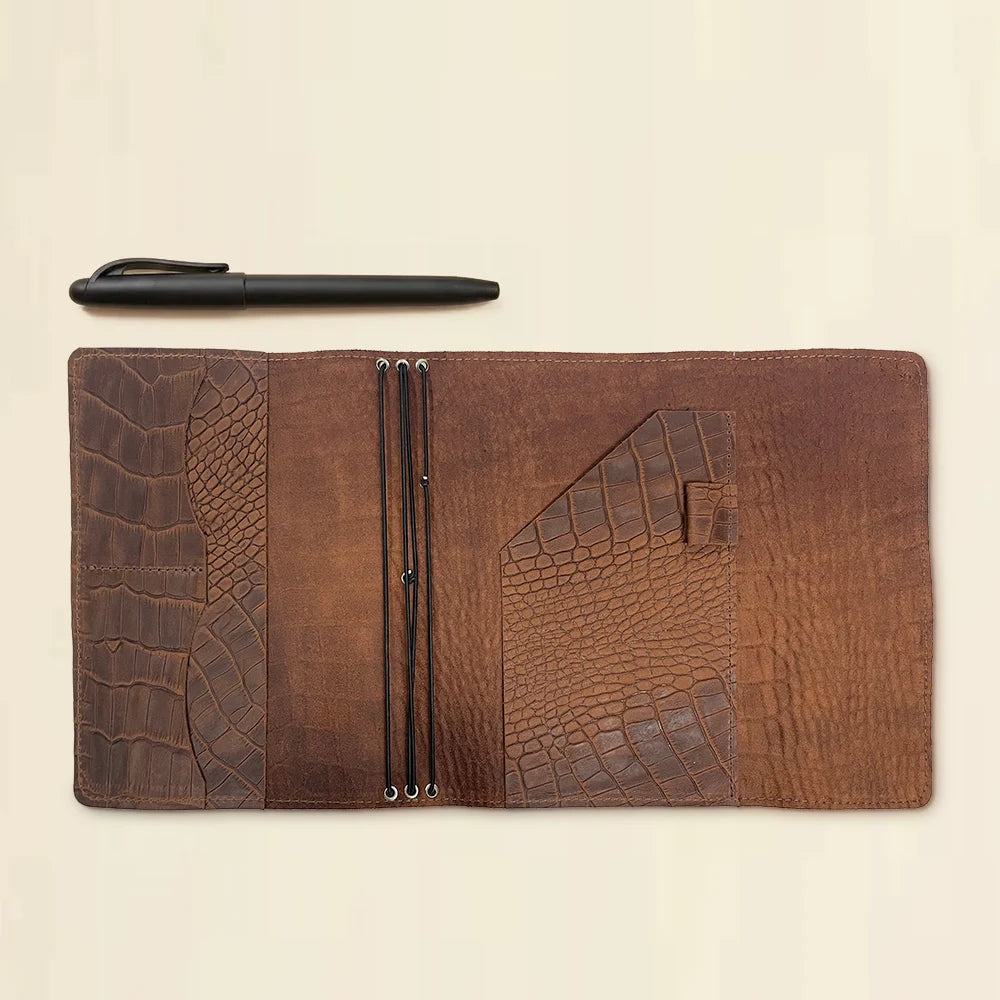 Rustic leather notebook cover designed with three elastic bands and interior storage pockets.
