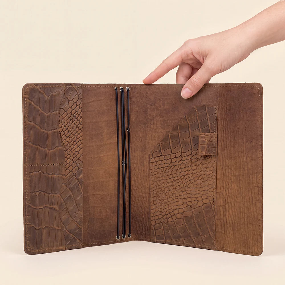 Leather travel notebook cover featuring three elastic bands and multiple interior compartments.