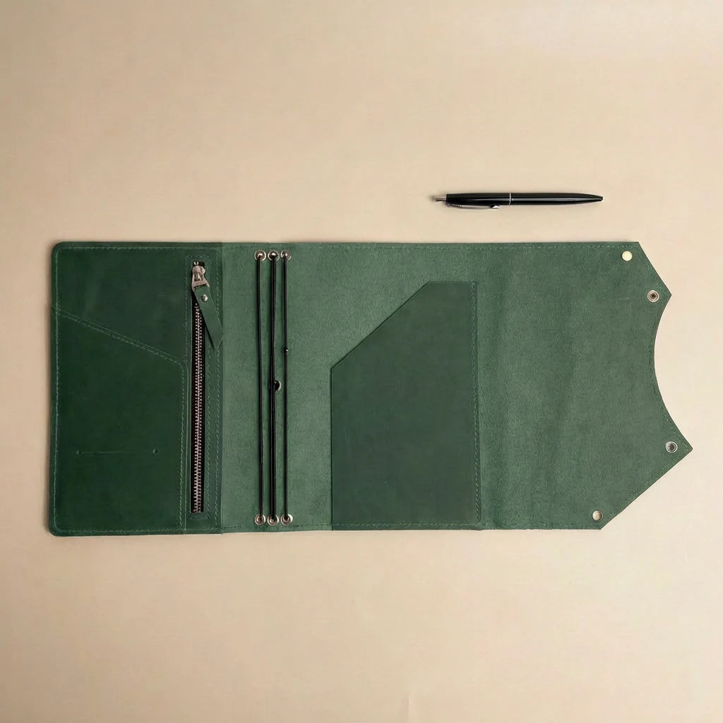Green leather journal cover with zipper pocket and pen on a beige background