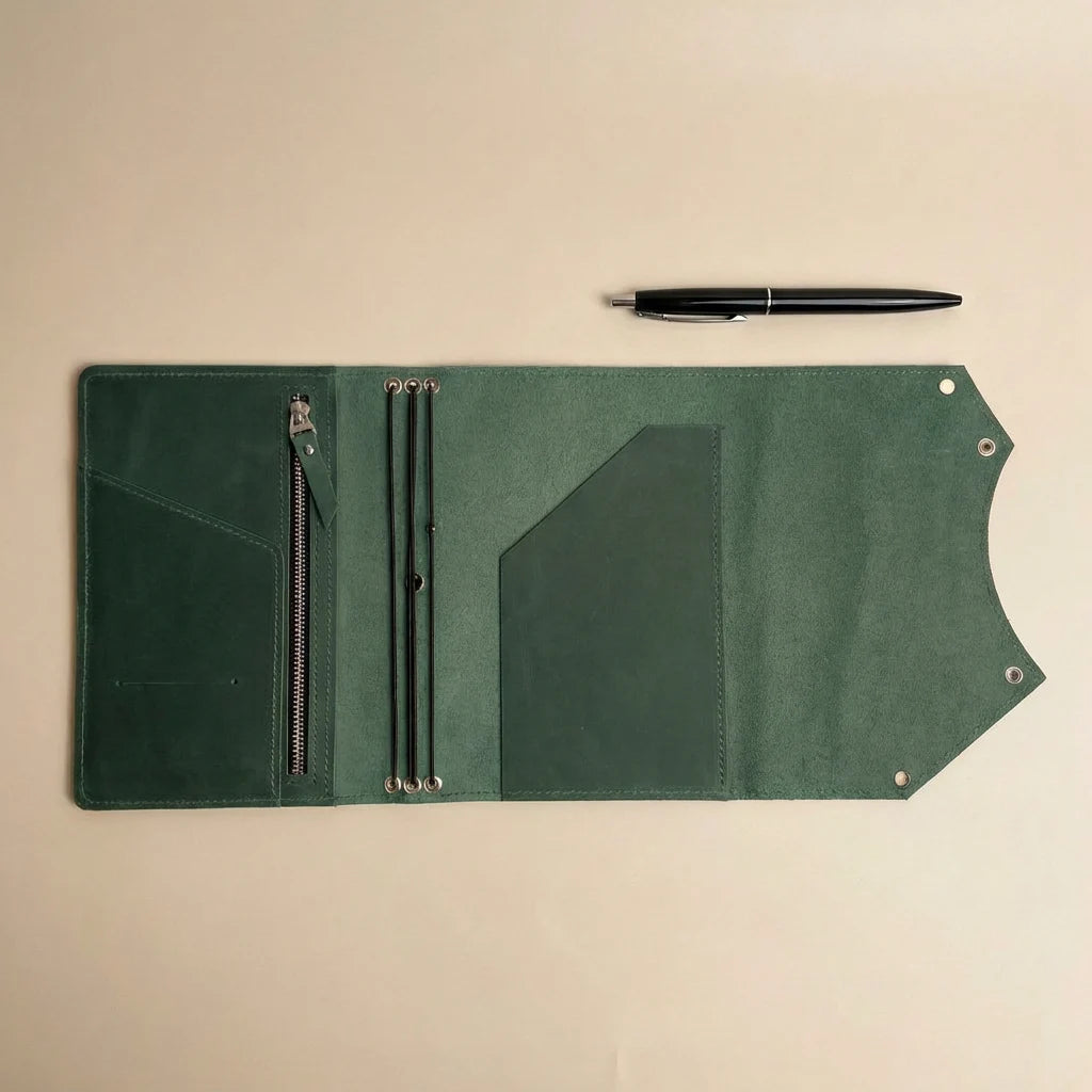 Green leather journal cover with zipper pocket and pen on a beige background