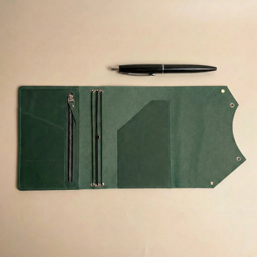 Green leather journal cover with pen and pen holder on a beige background