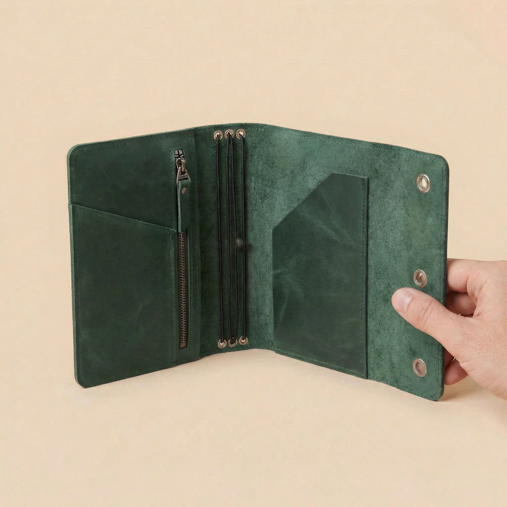 Green leather journal cover held open by a hand on a beige background