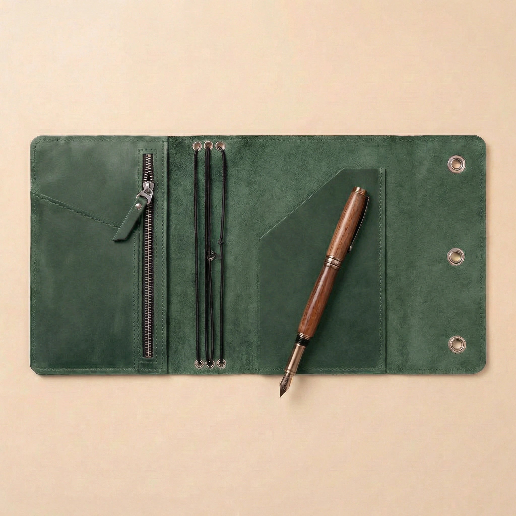 Green leather journal cover with a wooden pen on a beige background