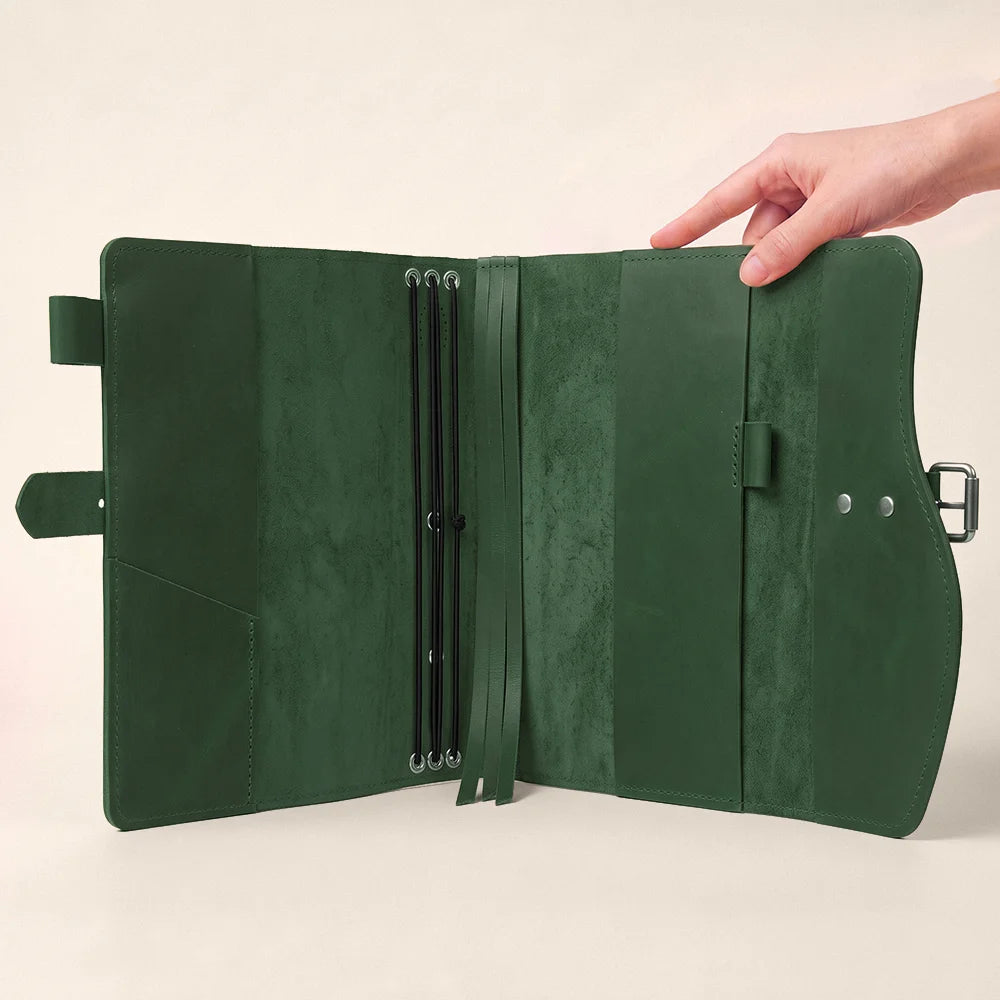 Genuine leather journal case displaying storage pockets, elastic pen loop, integrated bookmark, and exterior grip.