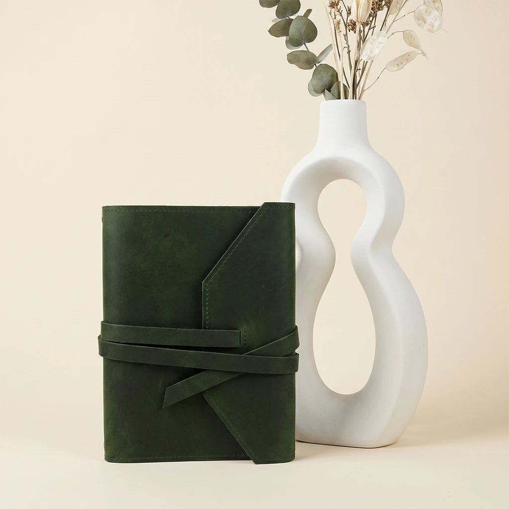 Reusable leather notebook wrap with elastic closure and attached pen loop.
