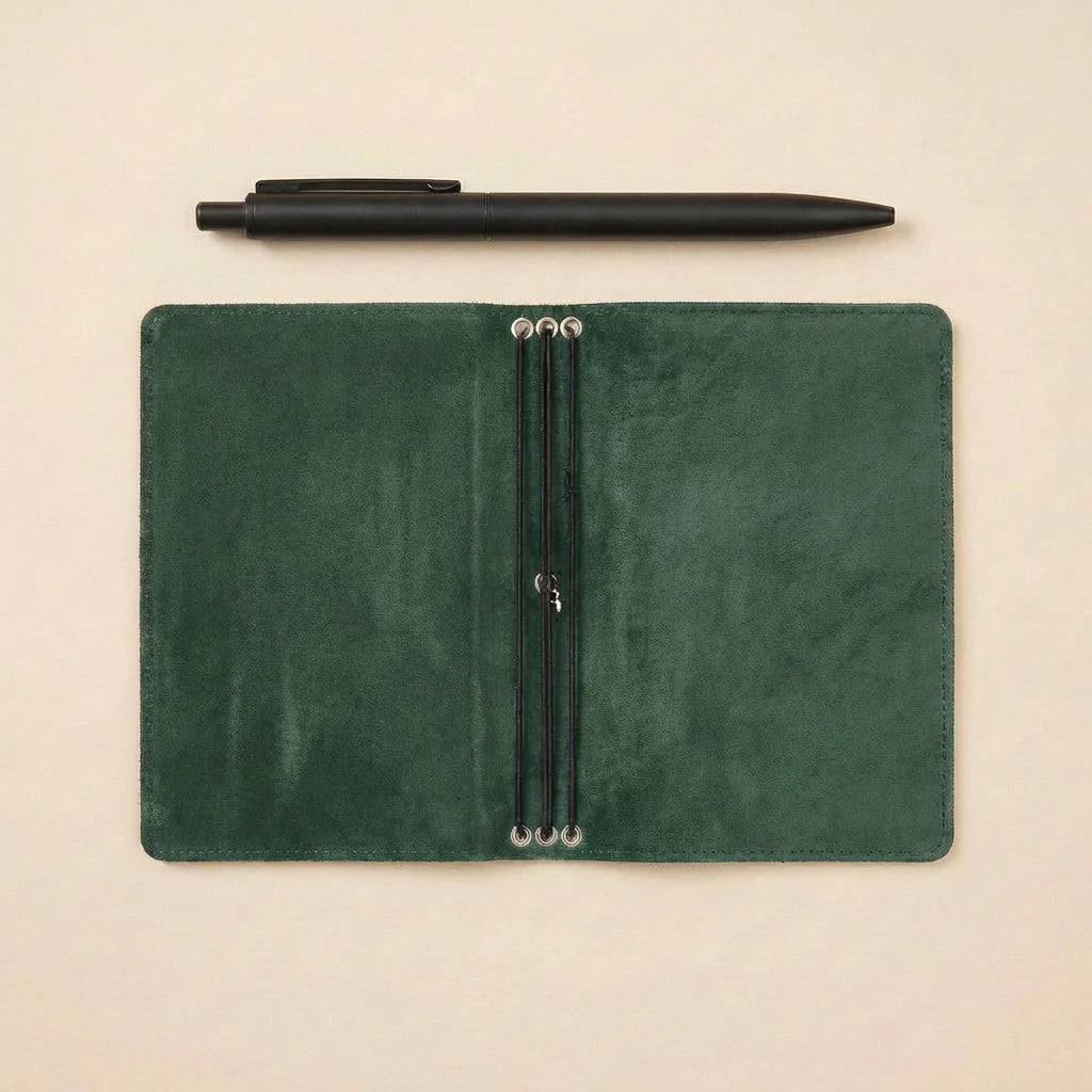 Green leather notebook with pen on a beige background