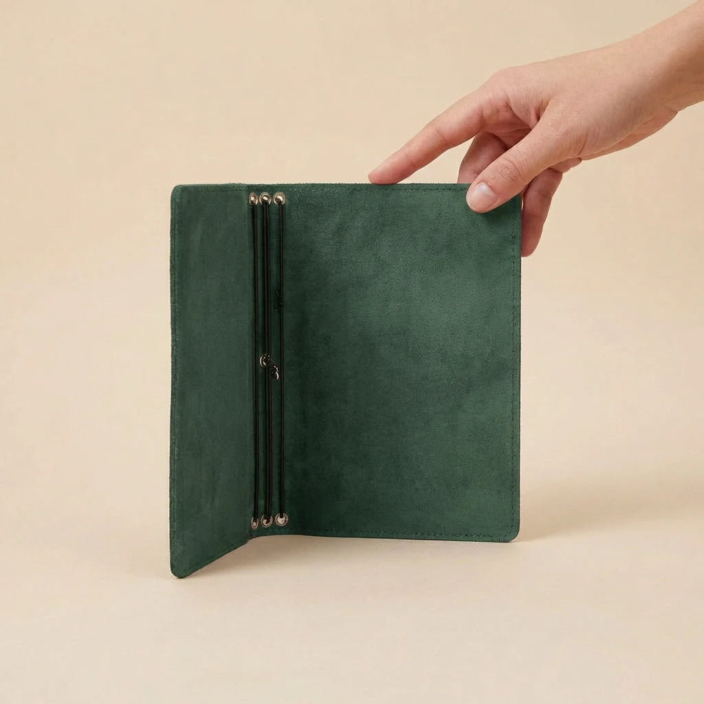 Green leather journal cover held by a hand on a beige background