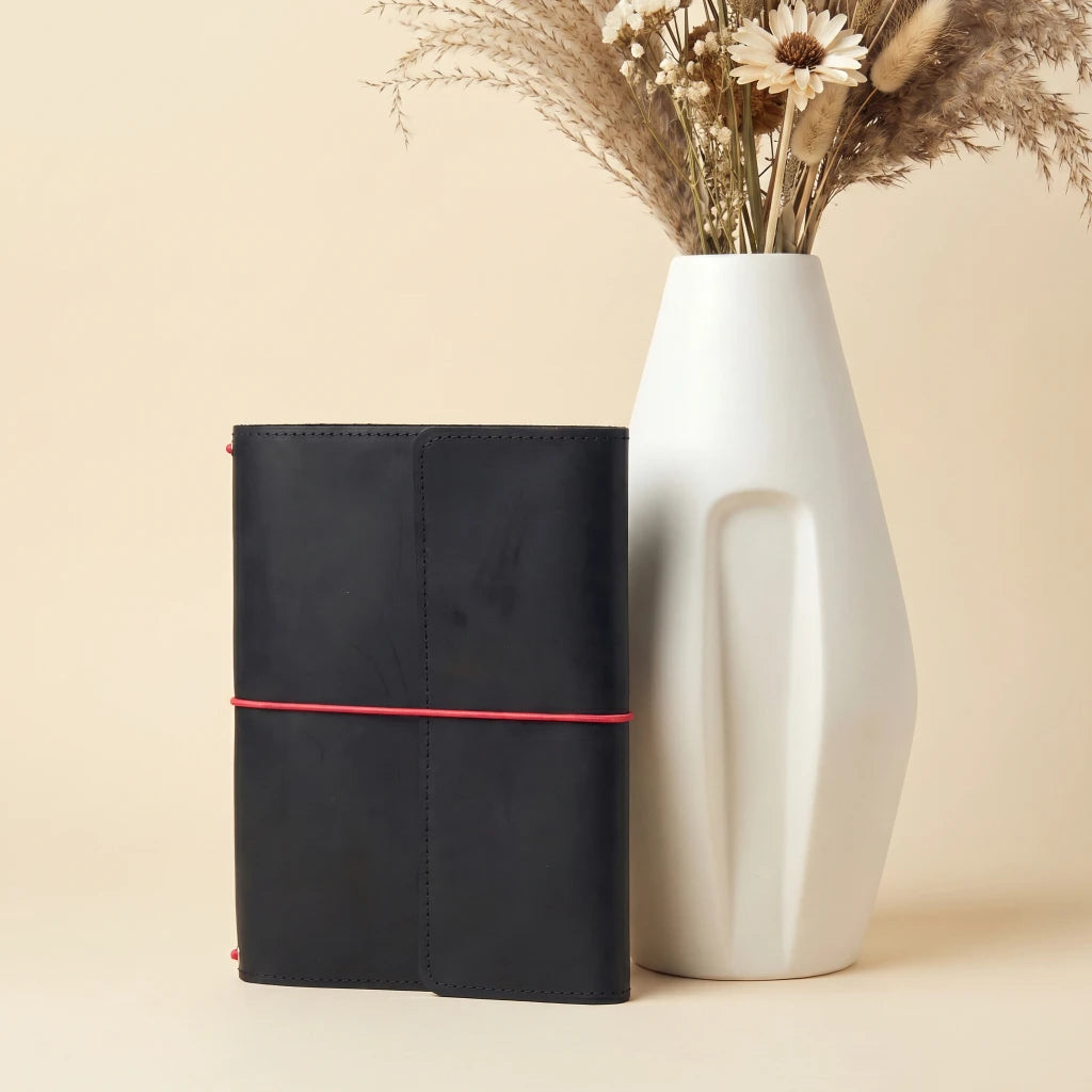 Handmade leather notebook cover with elastic cord system, storage pockets, and pen loop