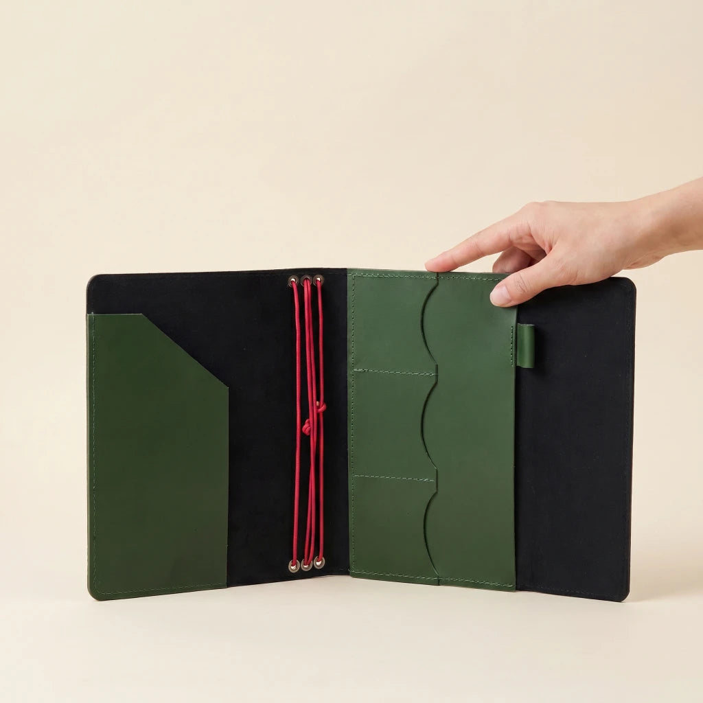 Premium leather notebook sleeve with elastic straps, storage sections, and pen loop
