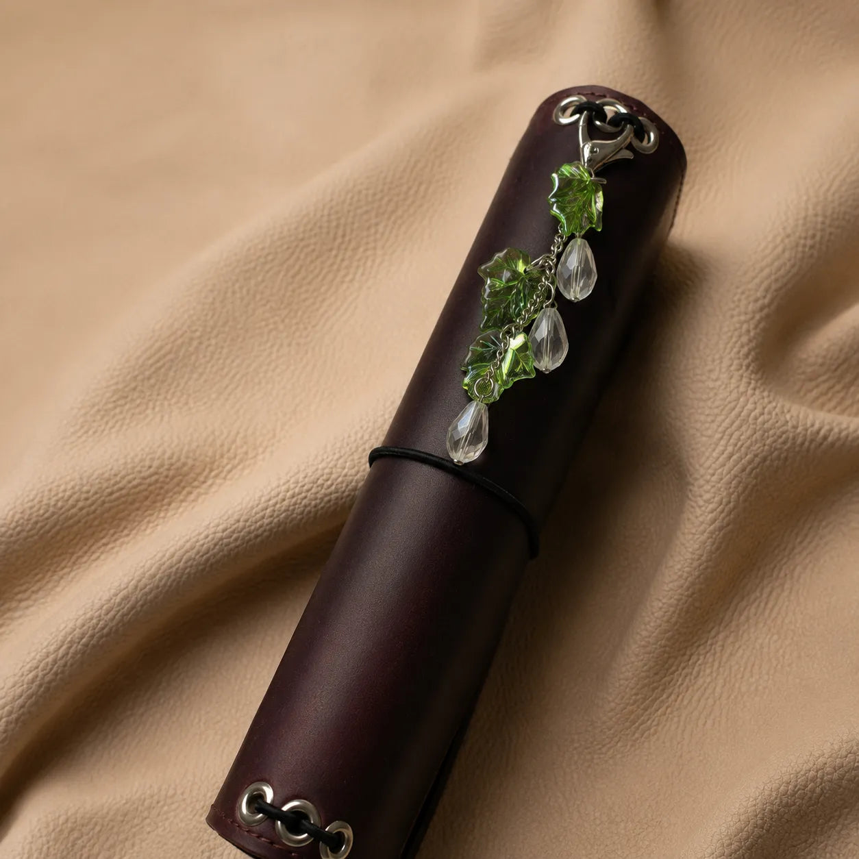 Leaf-shaped beaded journal charm attached to a notebook elastic, elegant handmade planner accessory.