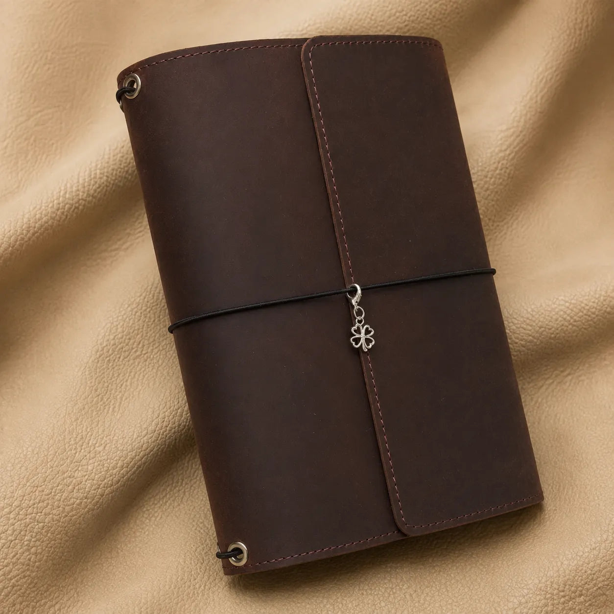 Clover journal charm attached to elastic bands on a genuine leather travel notebook.