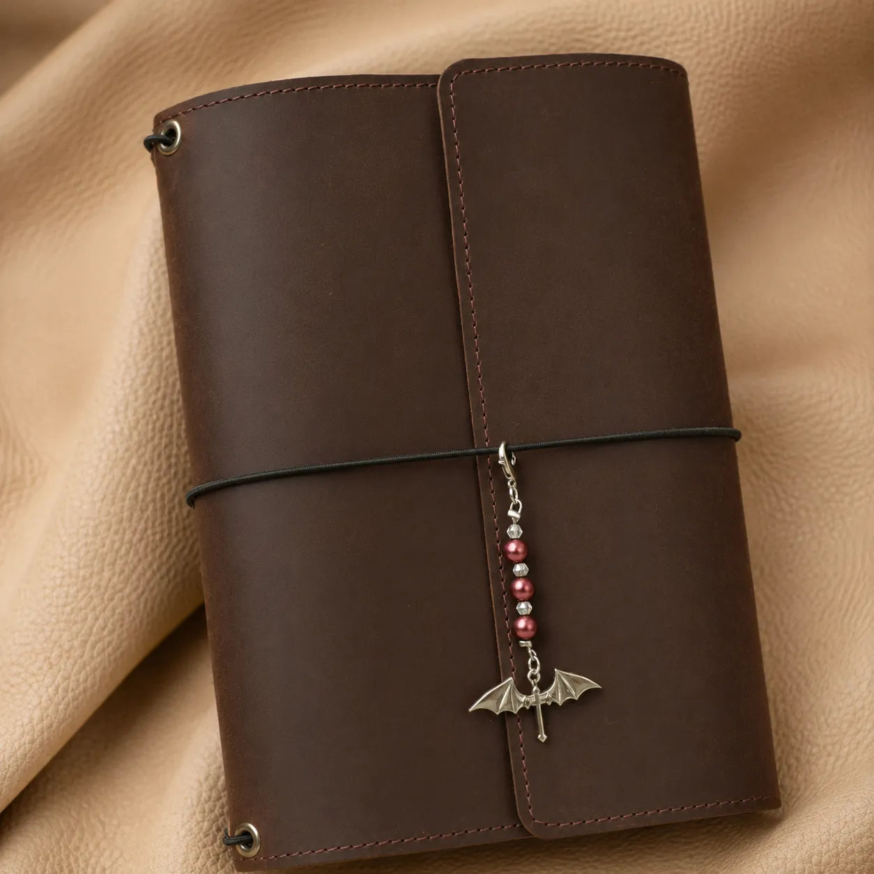 Decorative beaded journal charm accessory secured to notebook elastic for a stylish finishing touch.