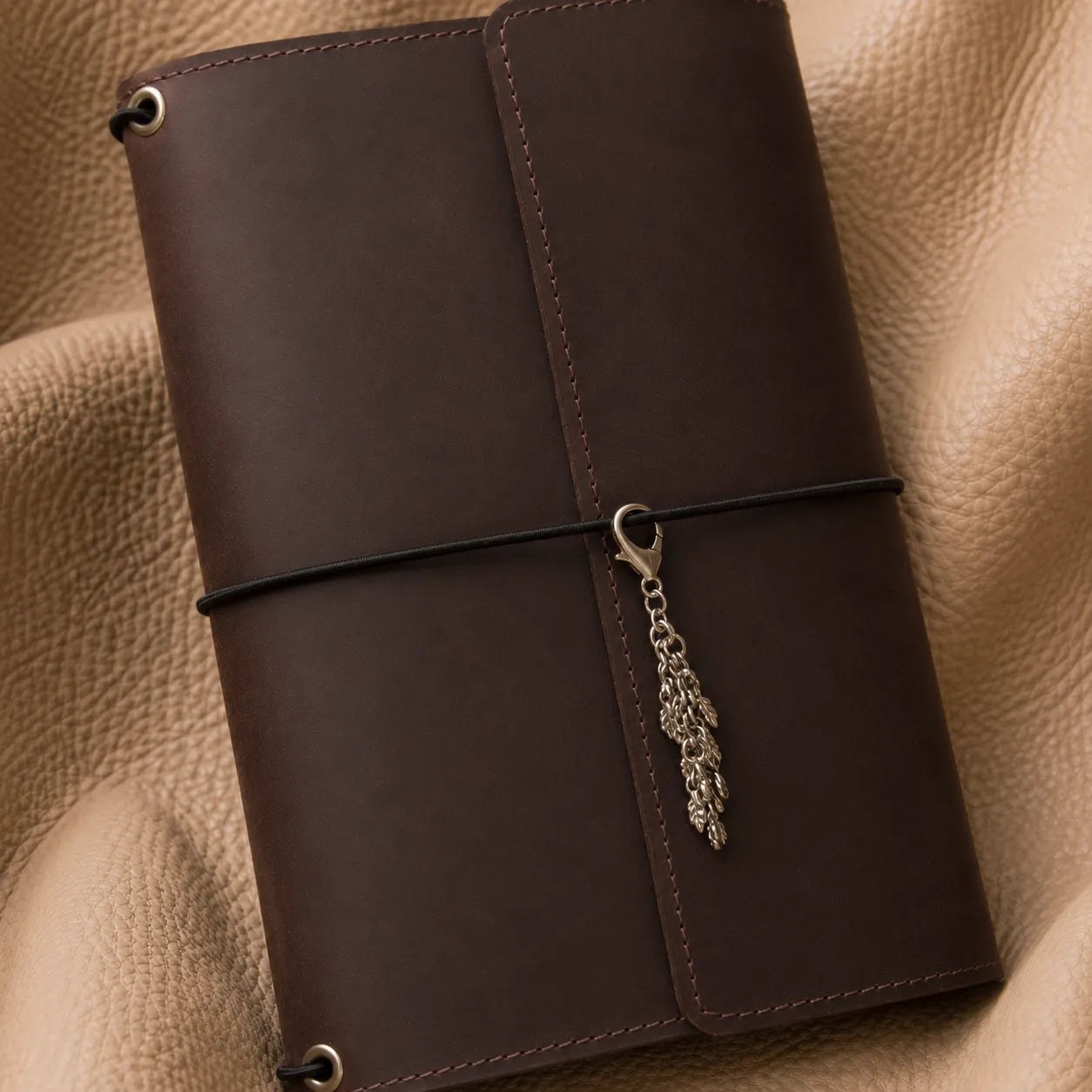Metal leaf bead notebook charm adding a stylish accent to refillable leather journal.