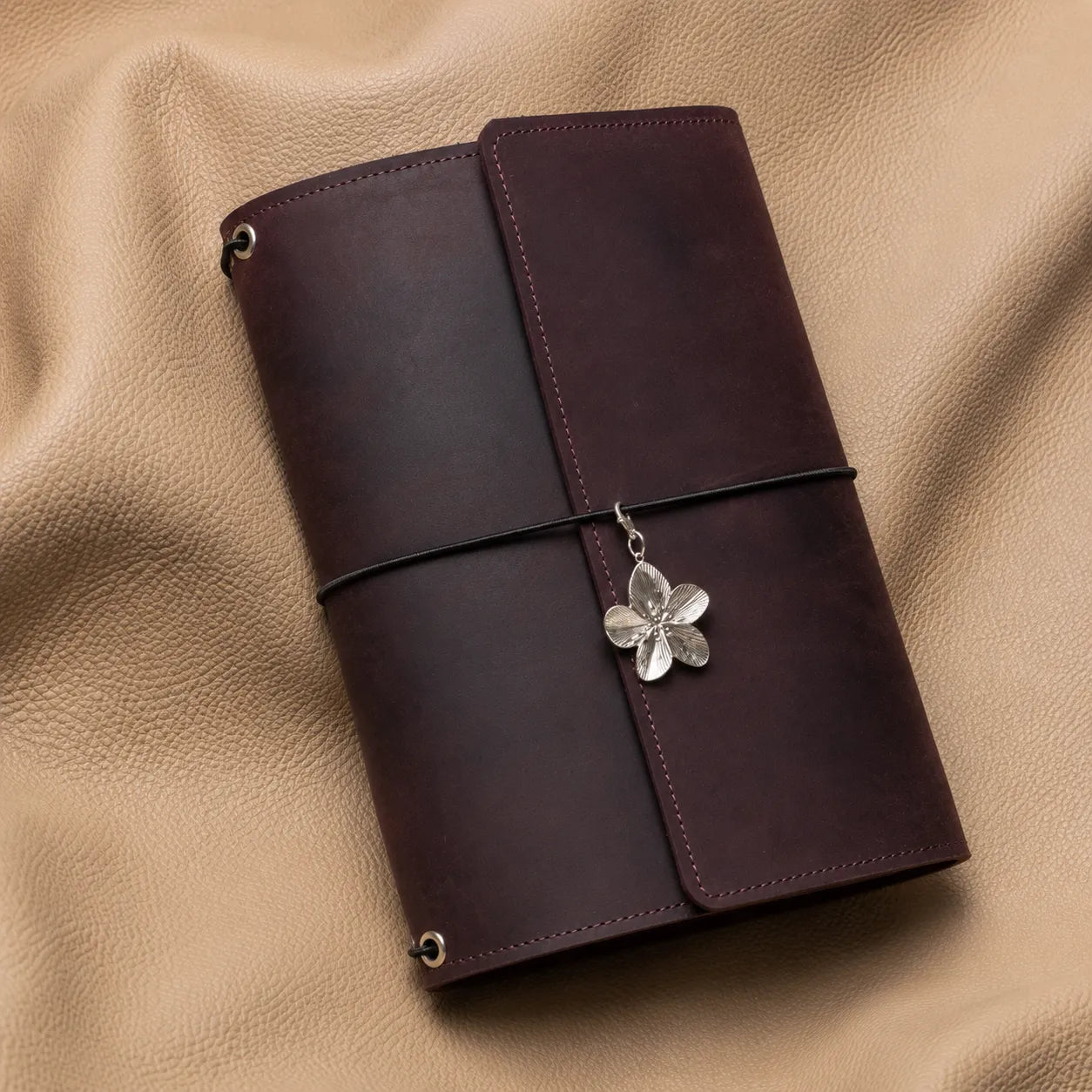 Flower-shaped journal charm bead attached to a leather notebook, elegant decorative planner accessory