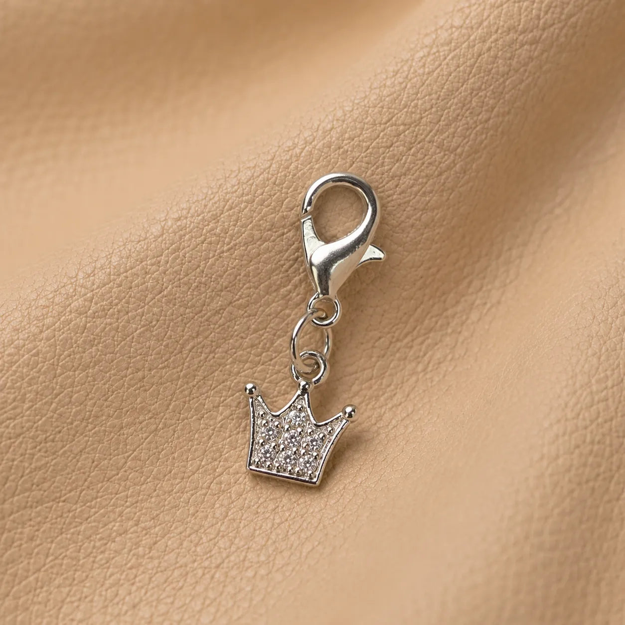 Decorative crown journal charm secured on notebook elastic bands, stylish handcrafted planner accessory.