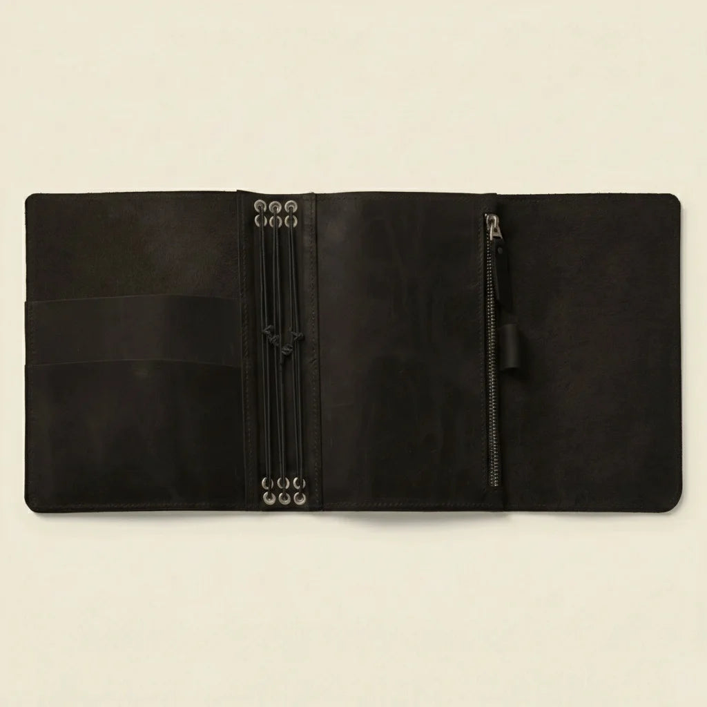 Black leather journal with zipper compartments on a beige background