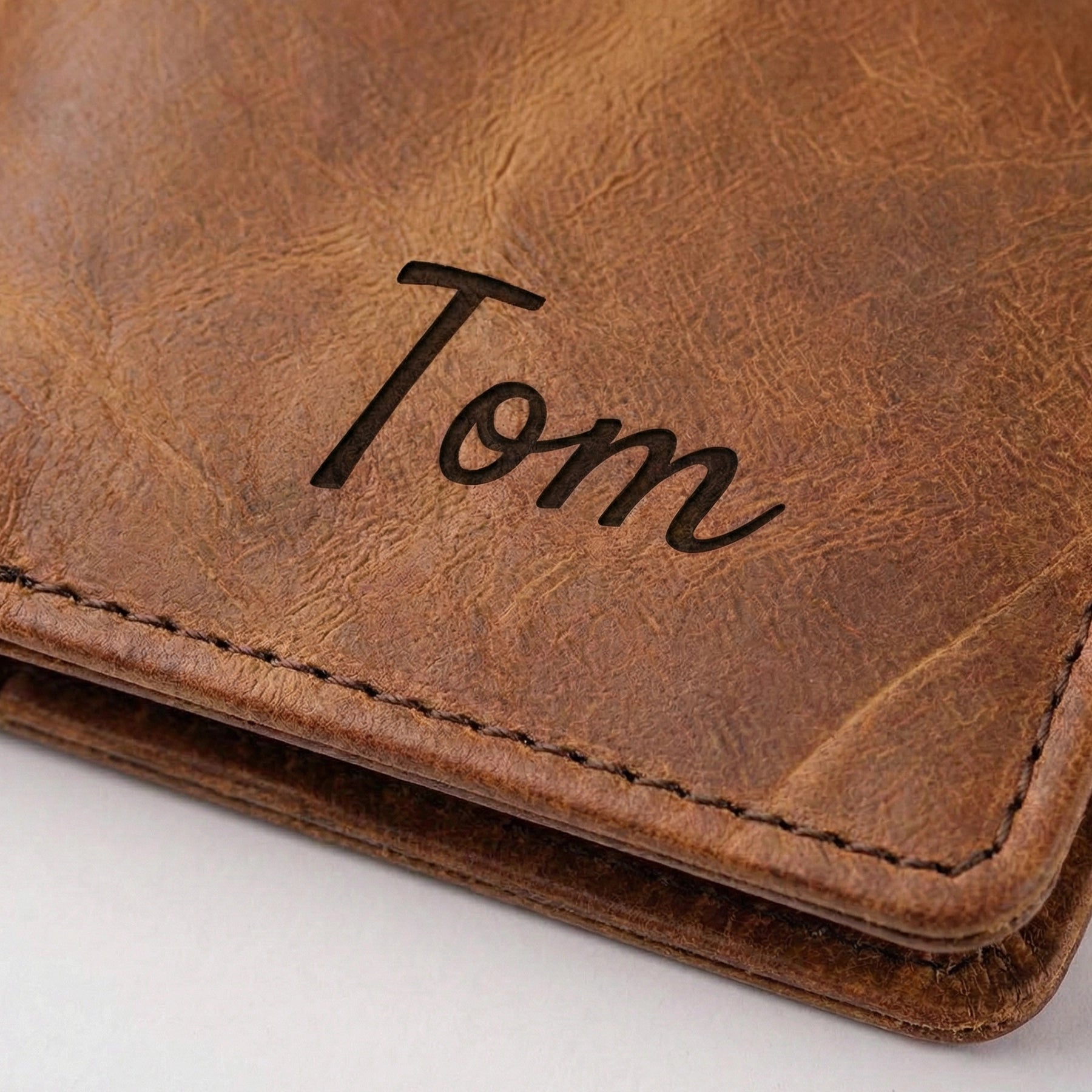 Brown leather journal cover with 'Tom' engraved on a white background