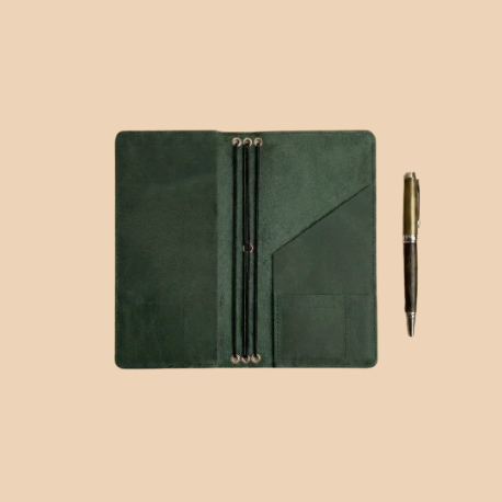 Green leather notebook and pen on a beige background