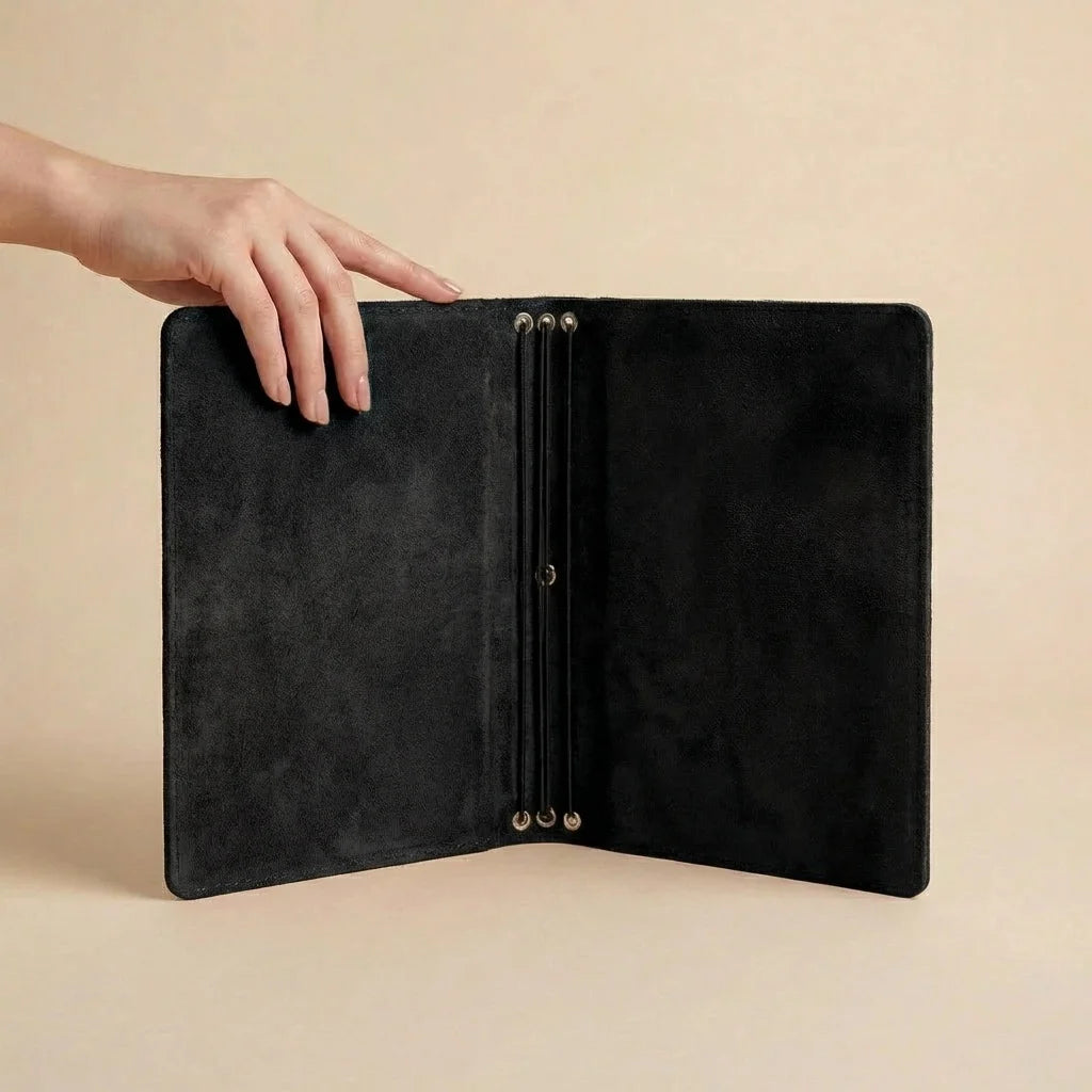 Black leather folder held open by a hand on a beige background